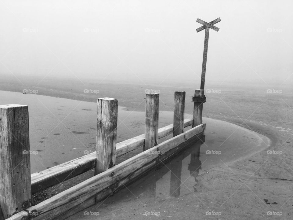 B&W groyne on the beach against a foggy background 