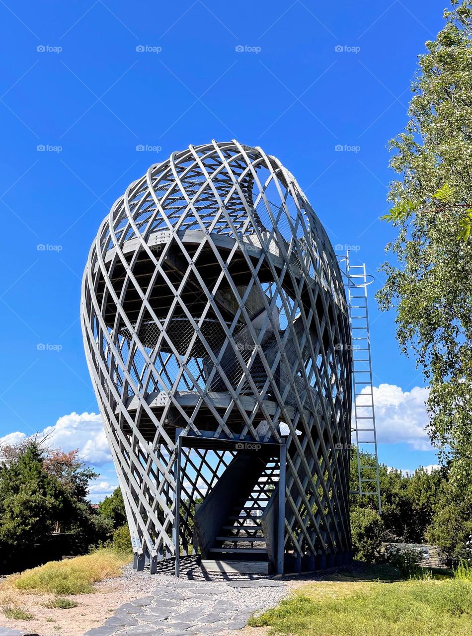 Crazy futuristic abstract wooden building oval cage in the middle of the bright clear day