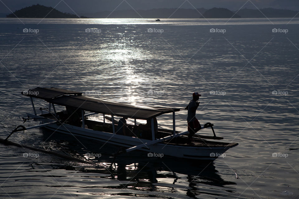 Silhouette of Amman piloting a boat at dusk