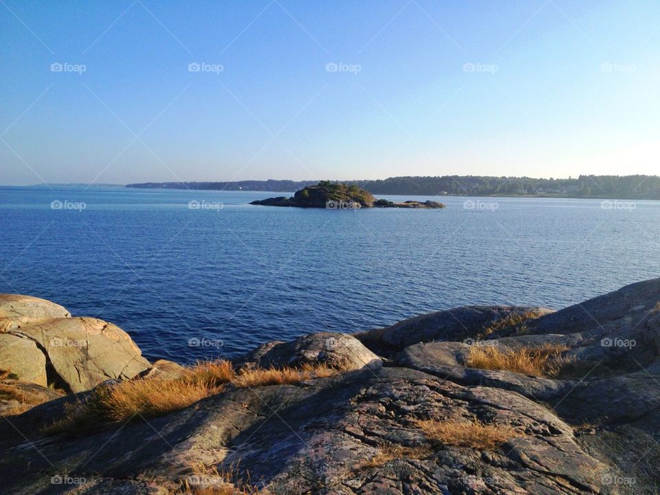 Rocks and sea against clear sky