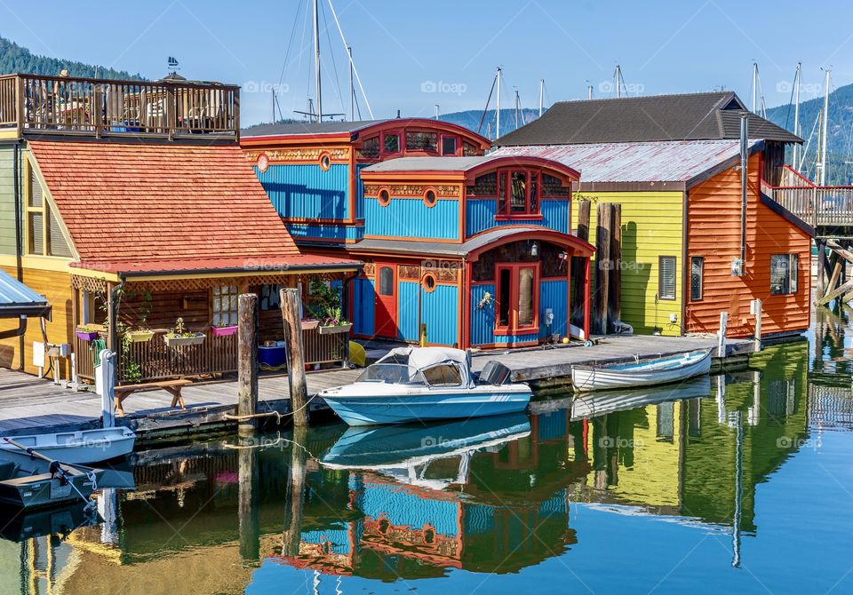 Floating homes and boat in blues, oranges and bright colours