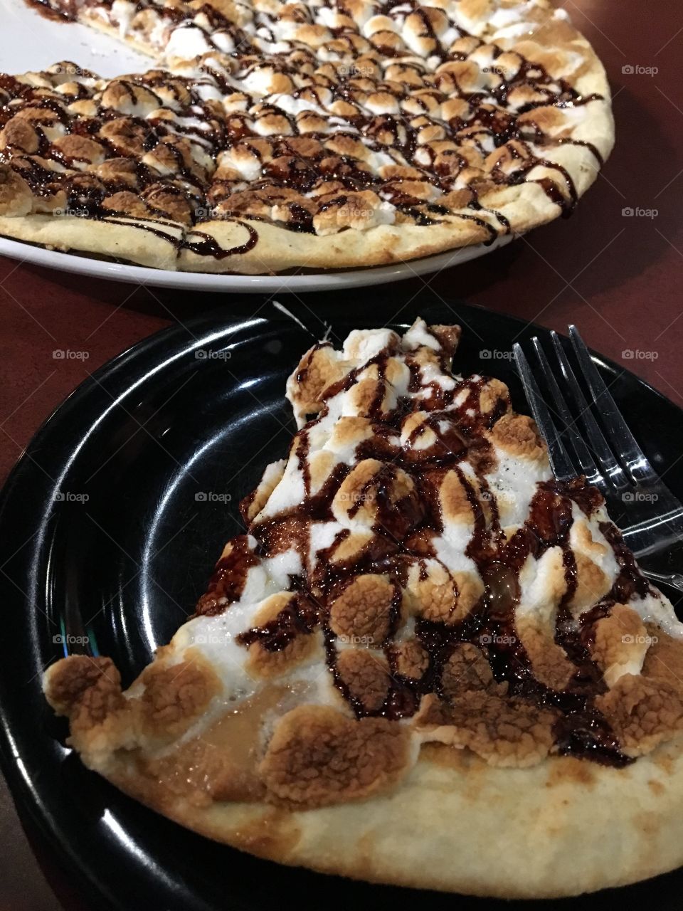 Pizza covered with peanut butter and topped with chocolate drizzle, graham cracker crumbles and marshmallows 