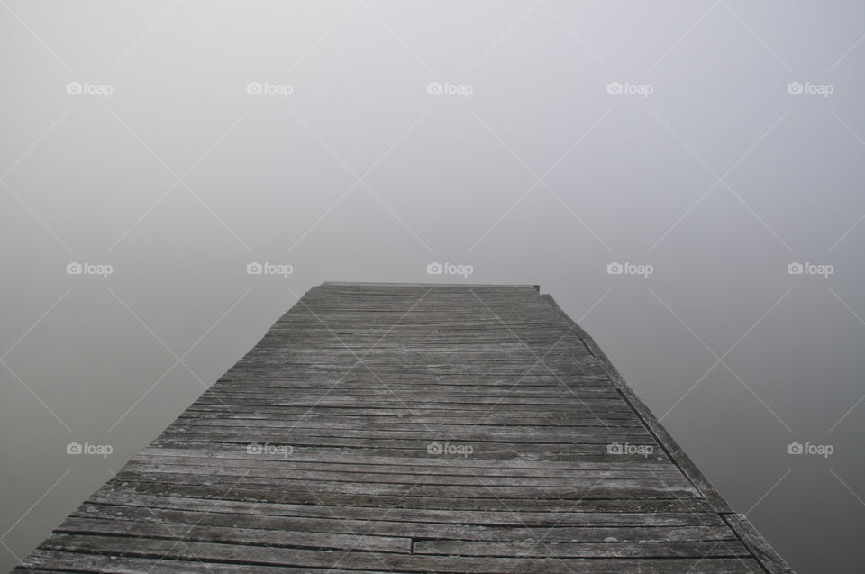 wooden pier over the lake in the foggy morning