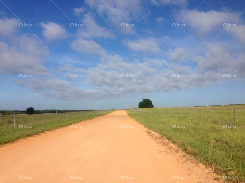 Beautiful day in the country. Dirt road and puffy clouds 