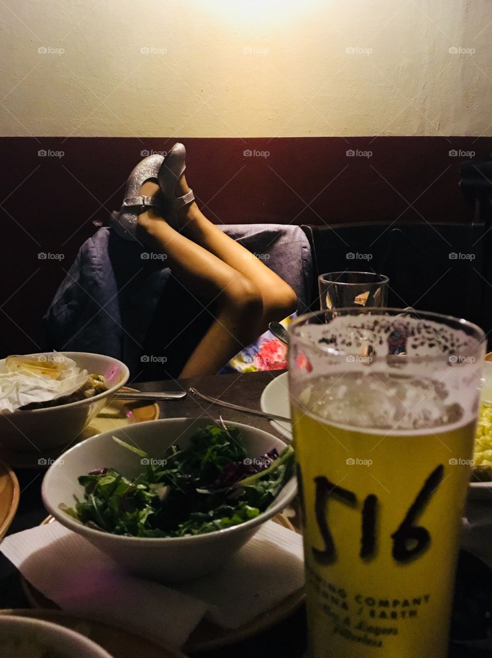 A child kicks up her feet in sparkling shoes at the dinner table in a restaurant 