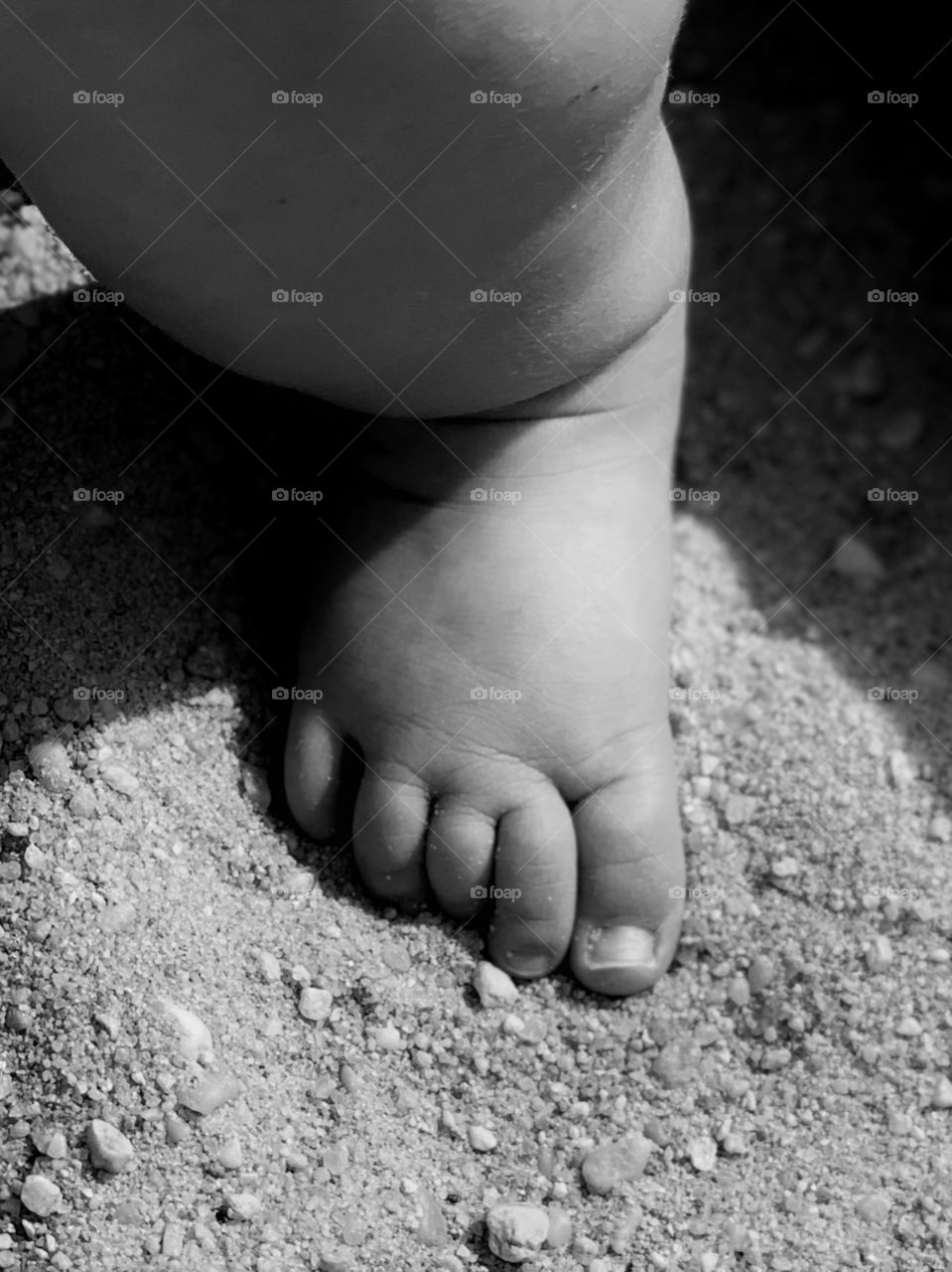 closeup of my daughter’s bare foot in sand at the beach on a warm sunny summer’s day