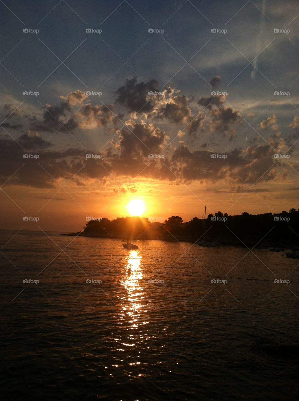Sunset colors reflect on calm waves, while fluffy little clouds play overhead.  Hvar Island, Croatia 2012