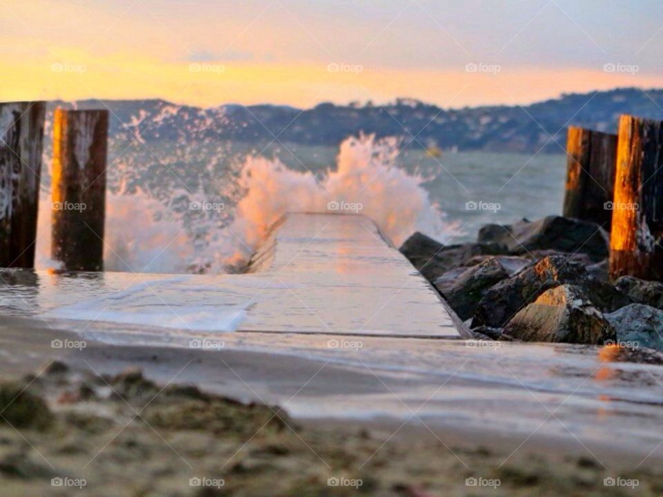Waves splashing on pier during sunset
