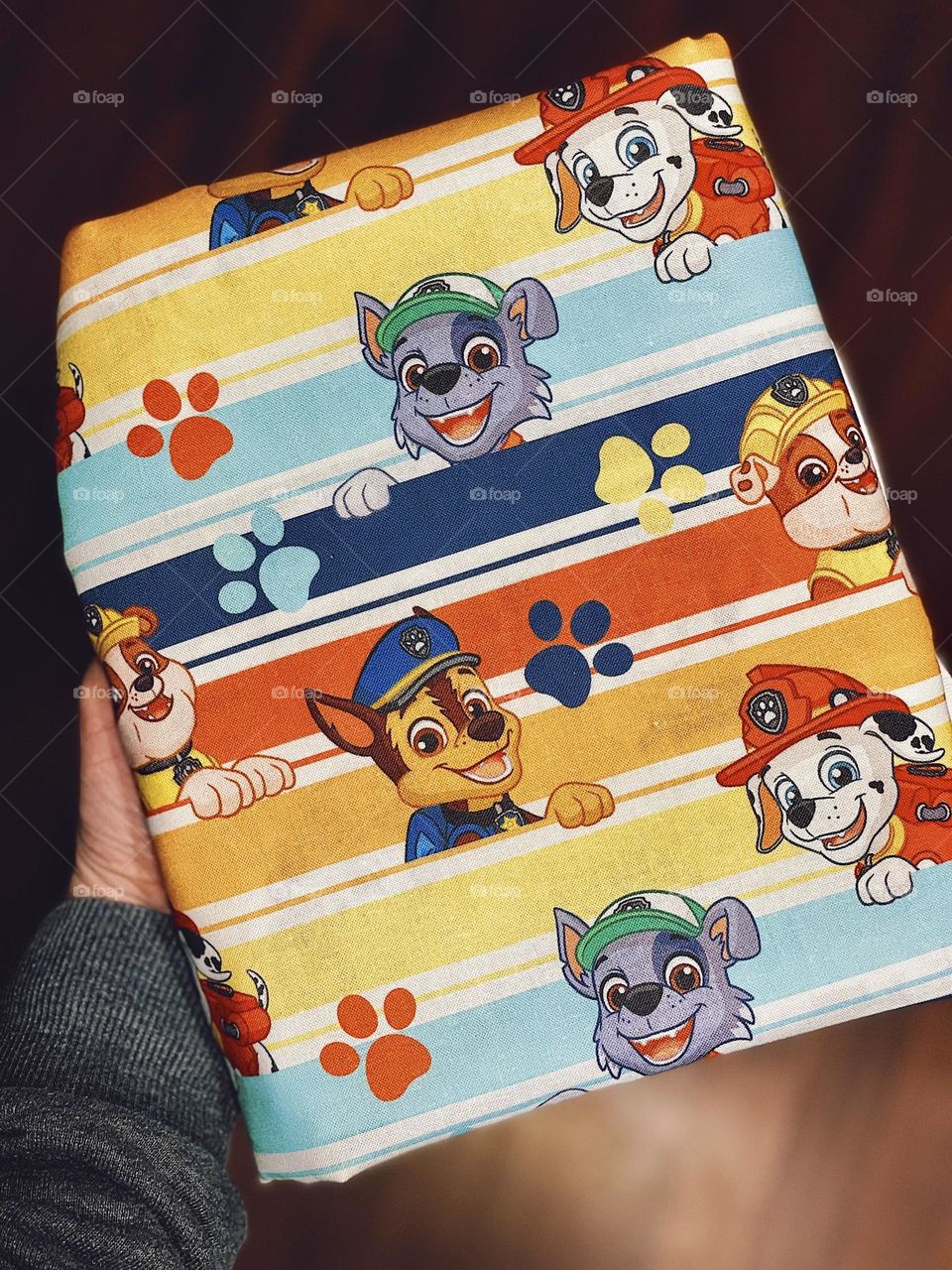 Woman holds Paw Patrol wrapped gift, making gift wrap out of cloth, cloth wrapping paper 