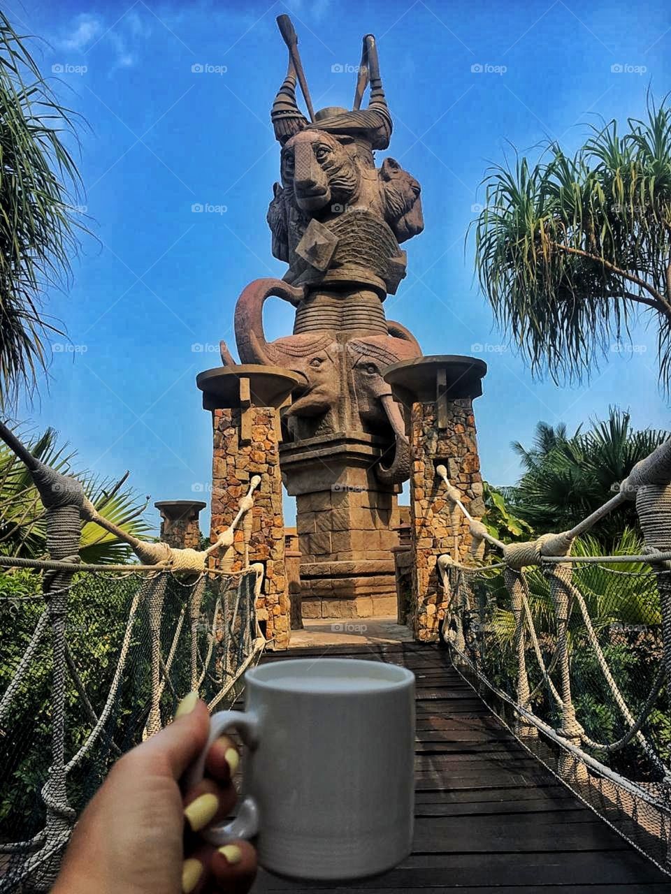 чашка кофе на фоне статуи в Тайланде