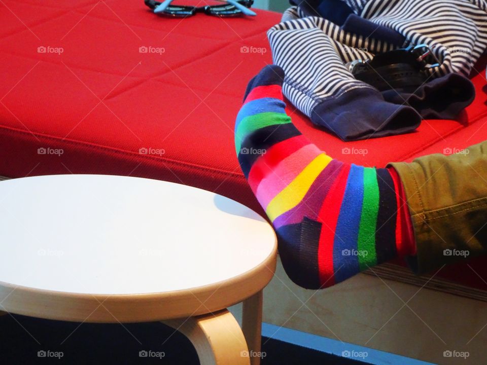 Bright and colorful rainbow sock, foot up on footrest in the library. 