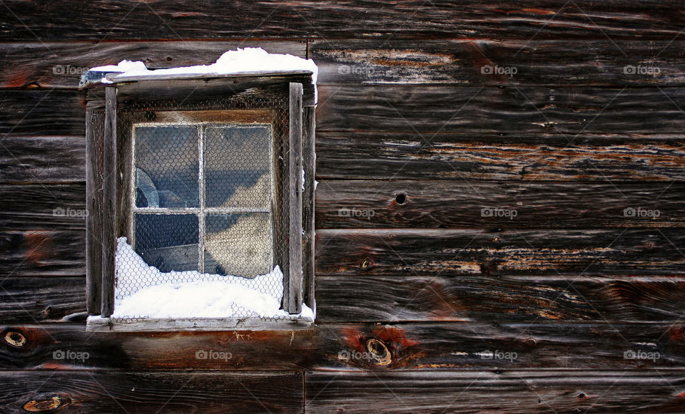 Old wood panel siding and snow covered window