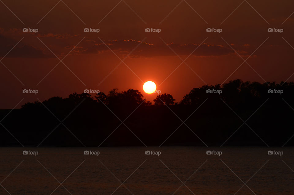 On a river boat cruise that winds down the Savannah river of Georgia a beautiful sunset descends upon the evening sky.