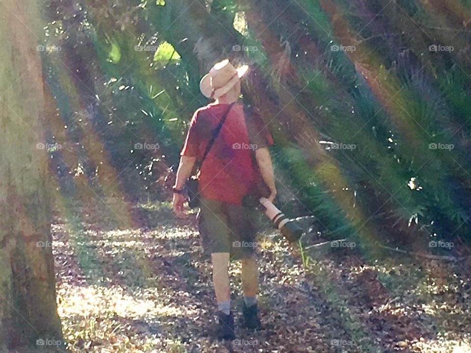 Photographer in the forest surrounded by the suns rainbows.