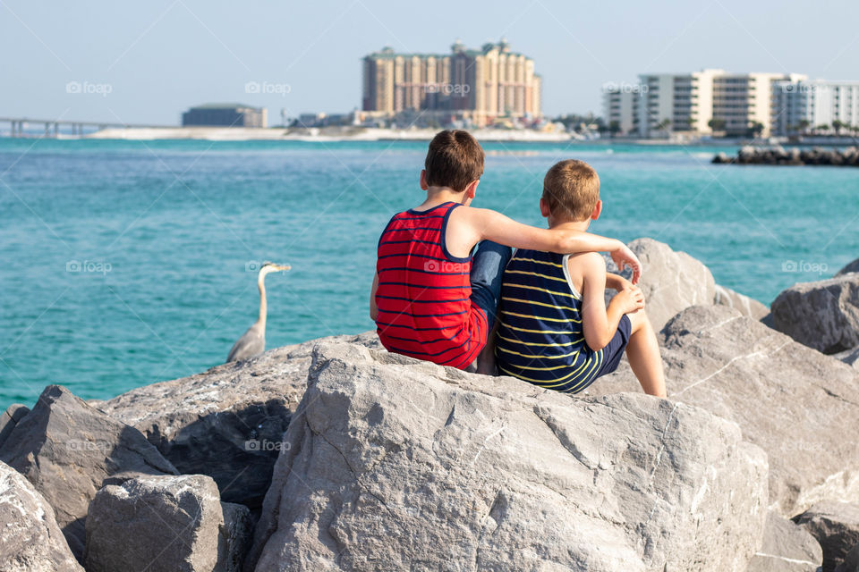 Brothers sitting at the beach on the rocks