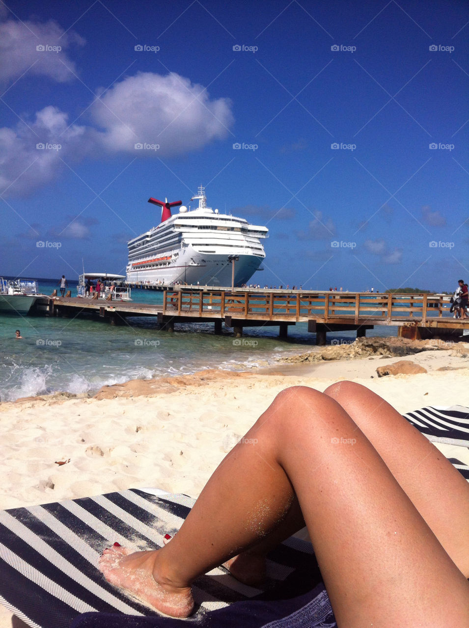 A woman's legs in front of a large cruise ship.