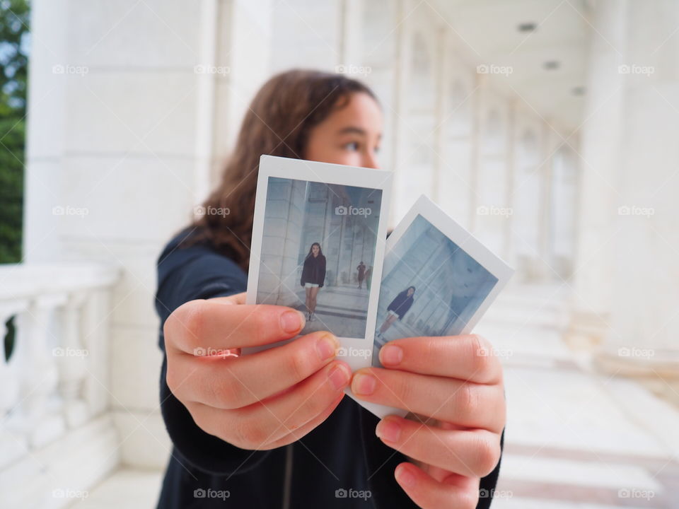 Girl holding two instant polaroid film pictures
