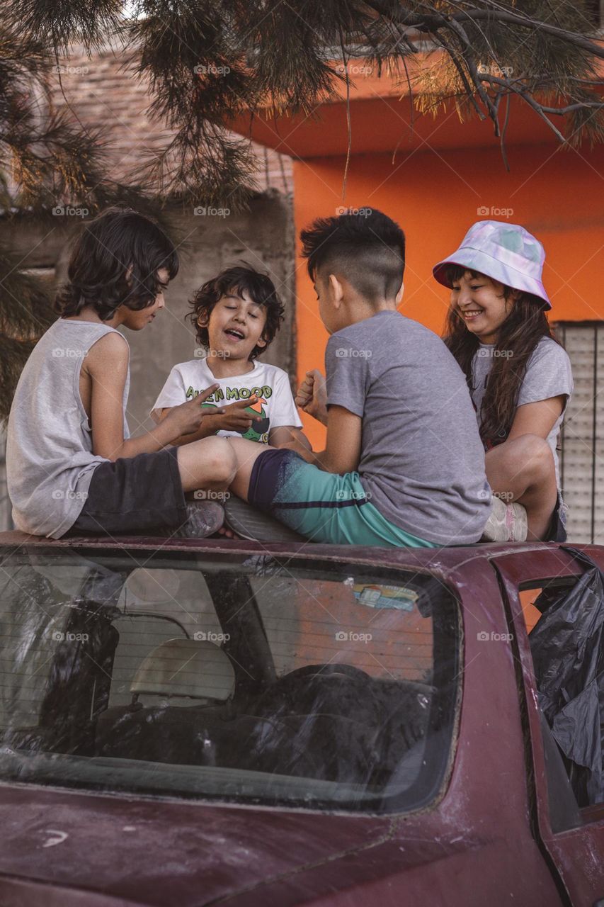 Niños jugando sobre automóvil abandonado