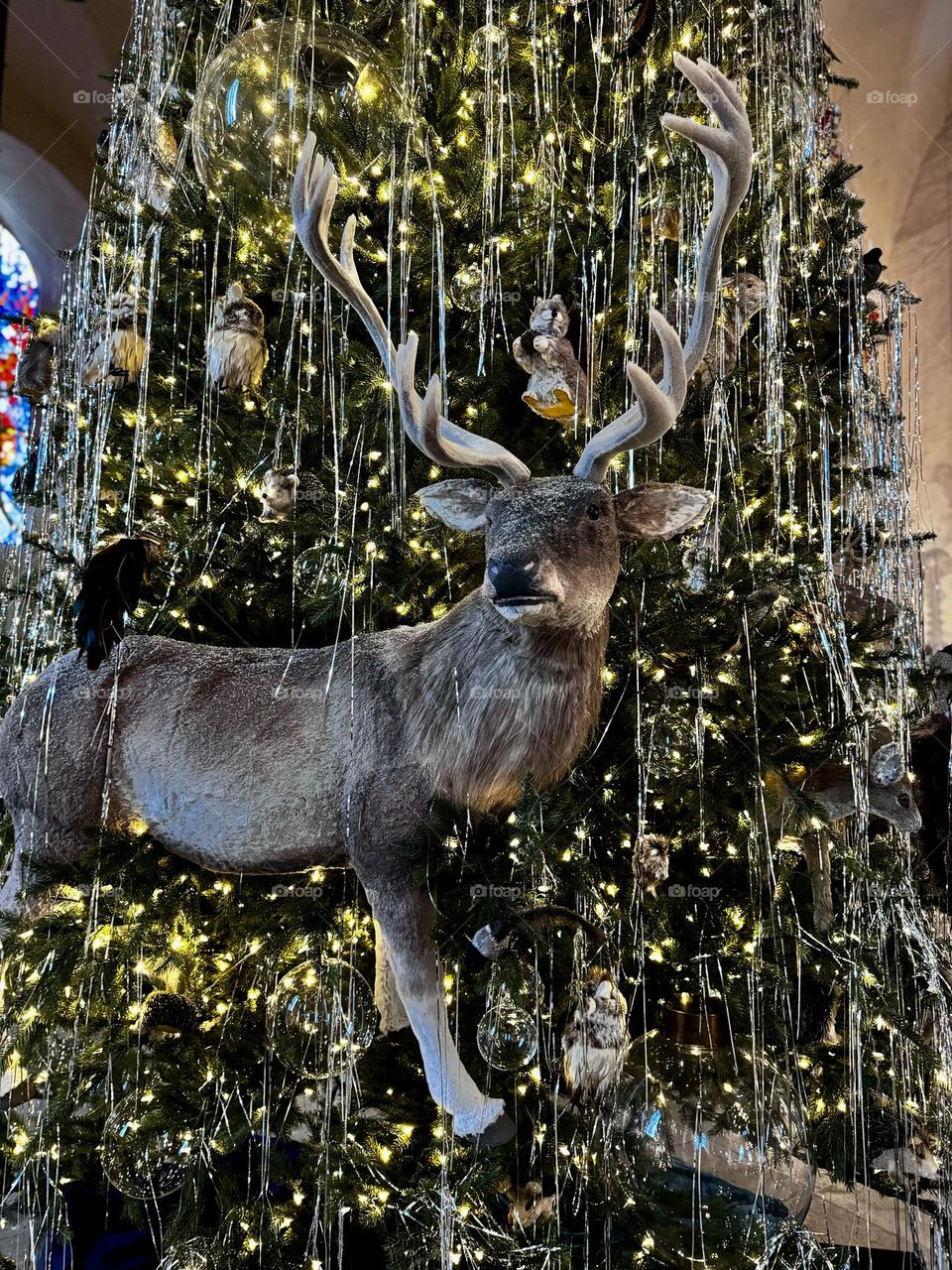 A huge toy elk as a Christmas decoration on a Christmas tree