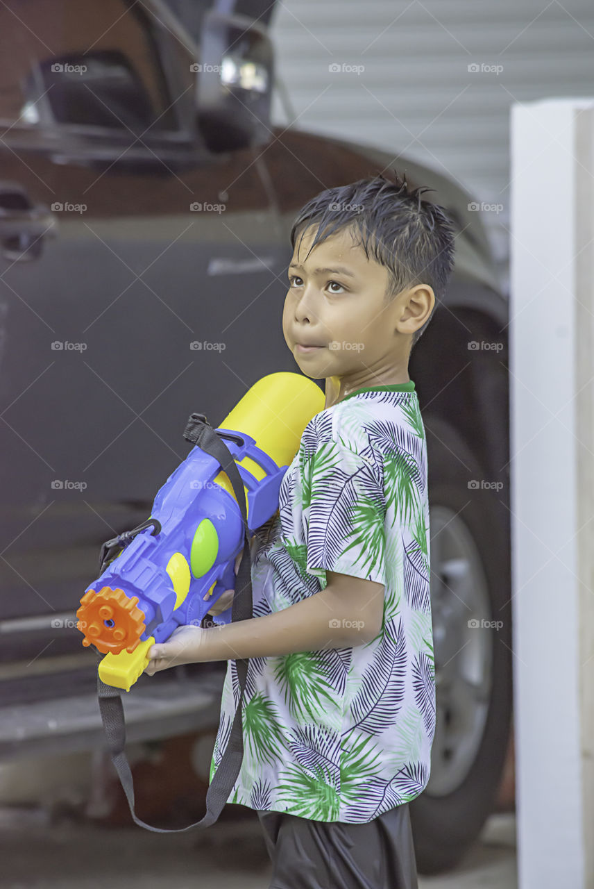 Asian boy holding a water gun play Songkran festival or Thai new year in Thailand.