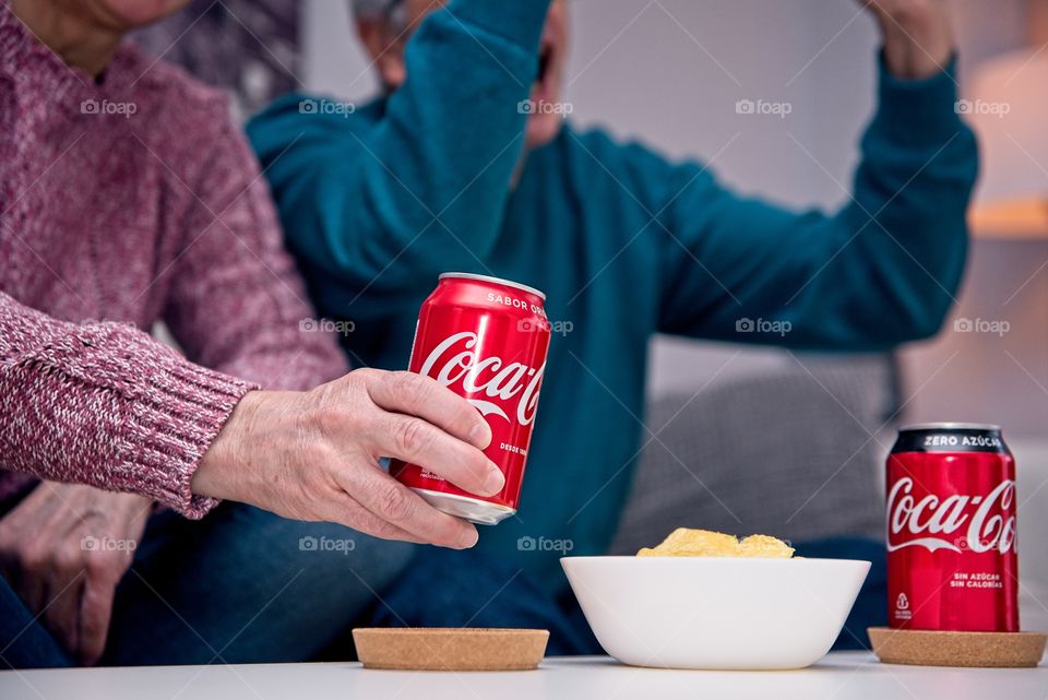 Couple eating a snack with Coca Cola while watching football