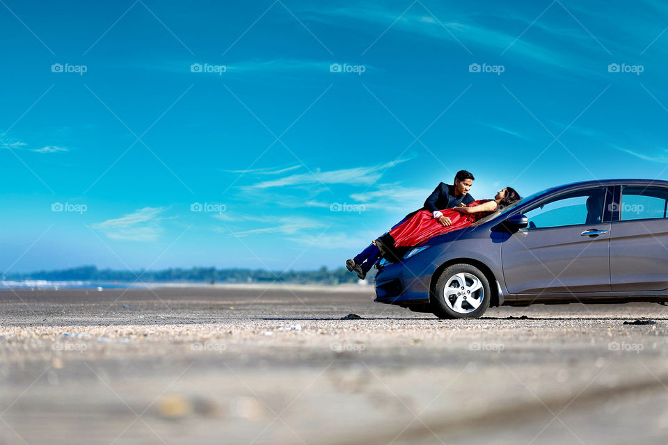 Couple lying on the car hood