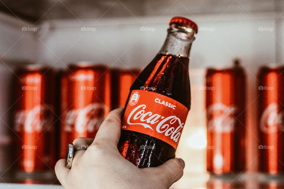 hand with coca cola in the fridge