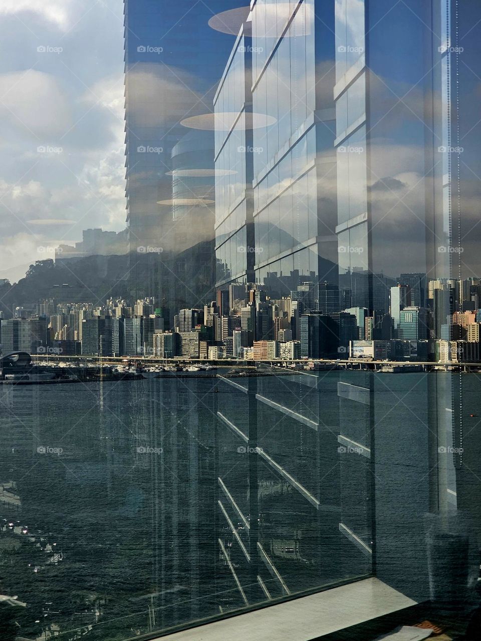 Looking over to East Kowloon city in Hong Kong on the other side of the Victoria Harbour through the reflection of a building