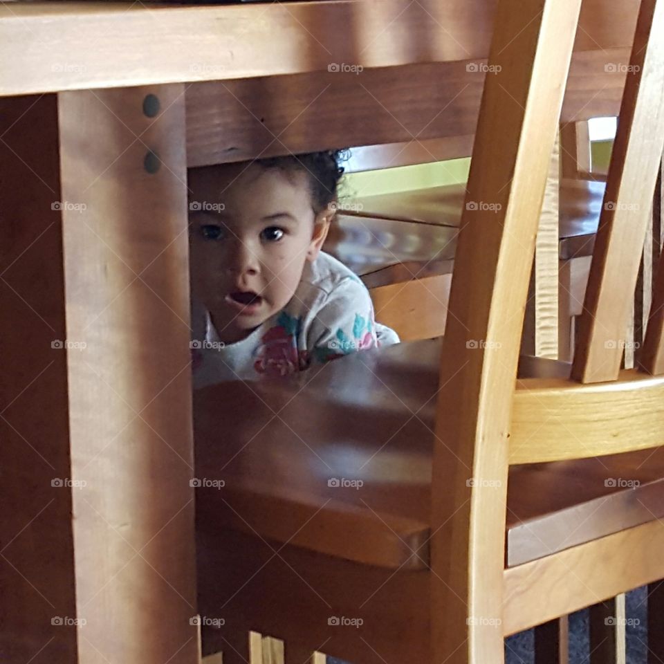 Little girl hiding under dining table