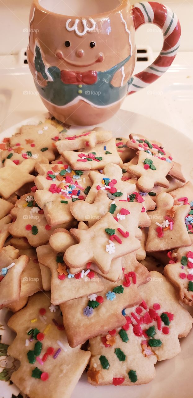 Fresh baked Christmas cookies with multicolored sprinkles with a cute gingerbread mug