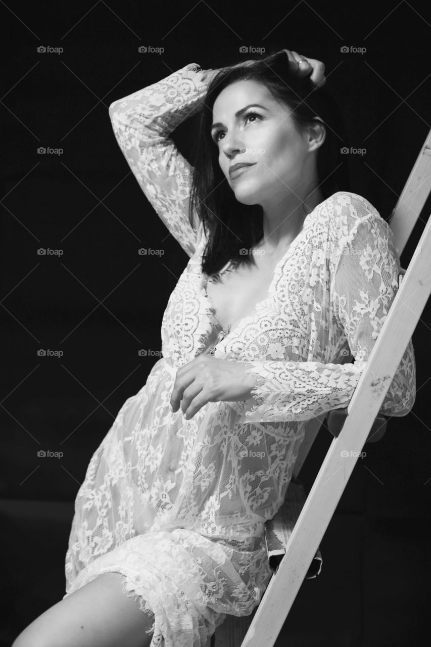 Woman in white lace dress on black background 