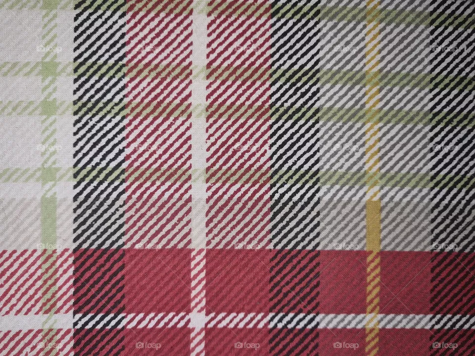 Scottish-like squares and check pattern of a fabric in green, yellow, red, white and dark blue colors.