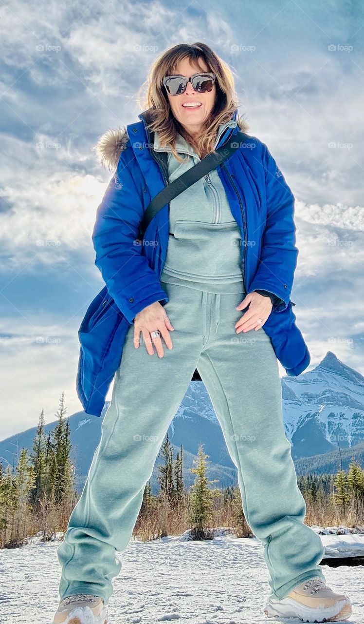 A beautiful woman poses in front of the Three Sisters in Banff National Park.