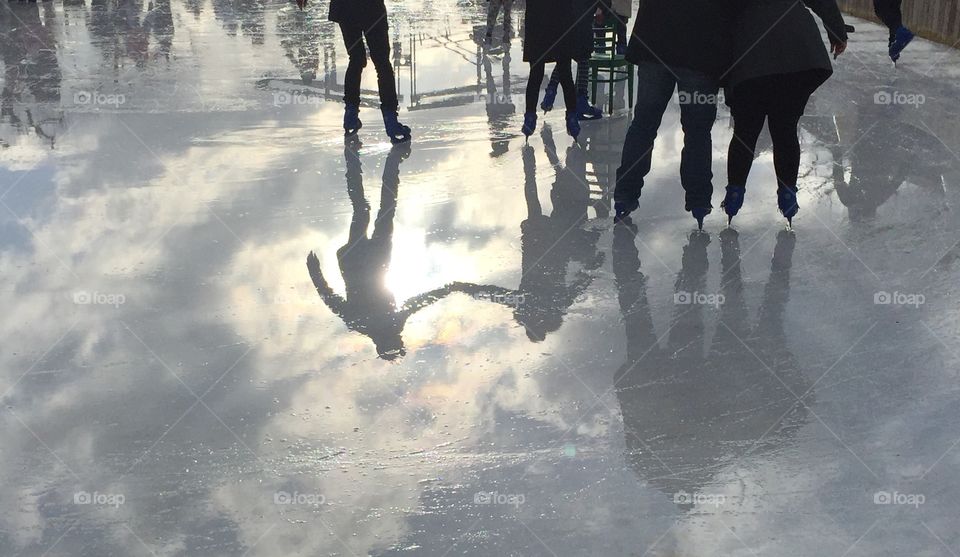 Ice skaters lovingly holding hands in reflection 