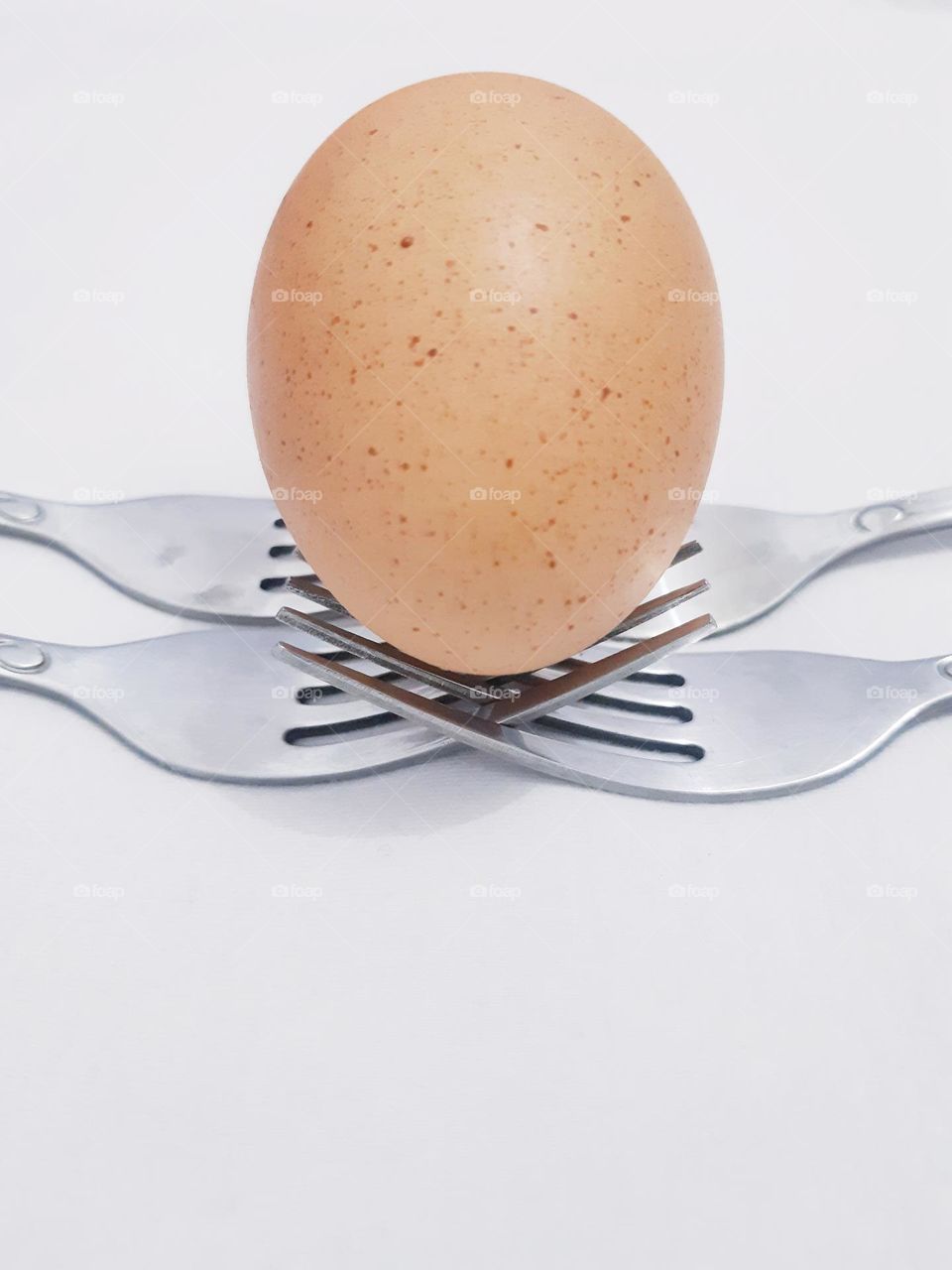 An egg stand on four forks against on white background