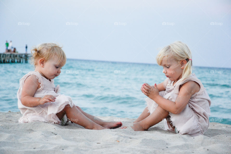 Close-up of two sister on sandy beach