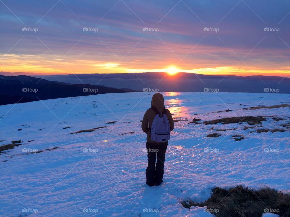 Woman hiker looking at the sunset in winter