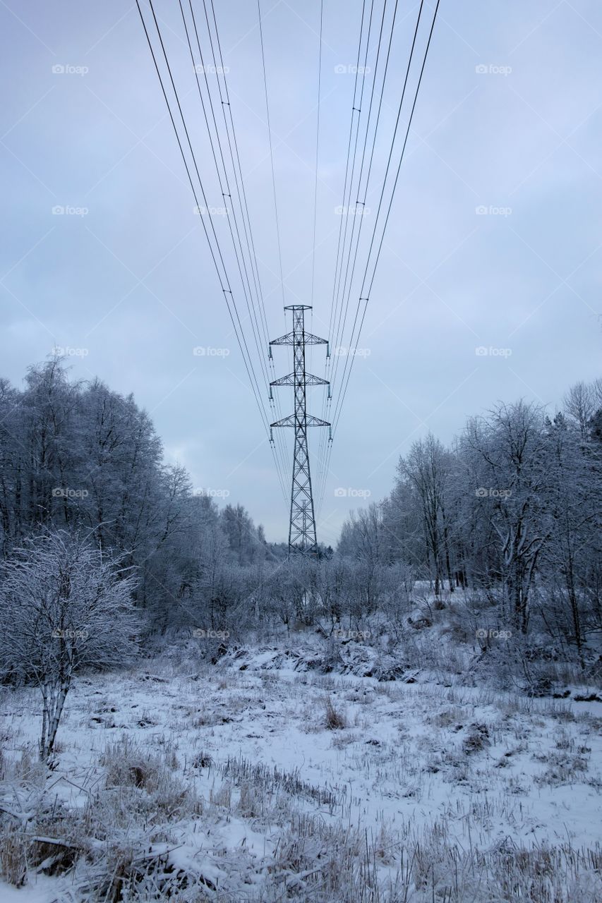 Helsinki, Finland - January 8, 2016: Power line or electricity grid in snowy city nature at suburbs of Lassila located in Western Helsinki, Finland on a winter evening on January 8, 2016.