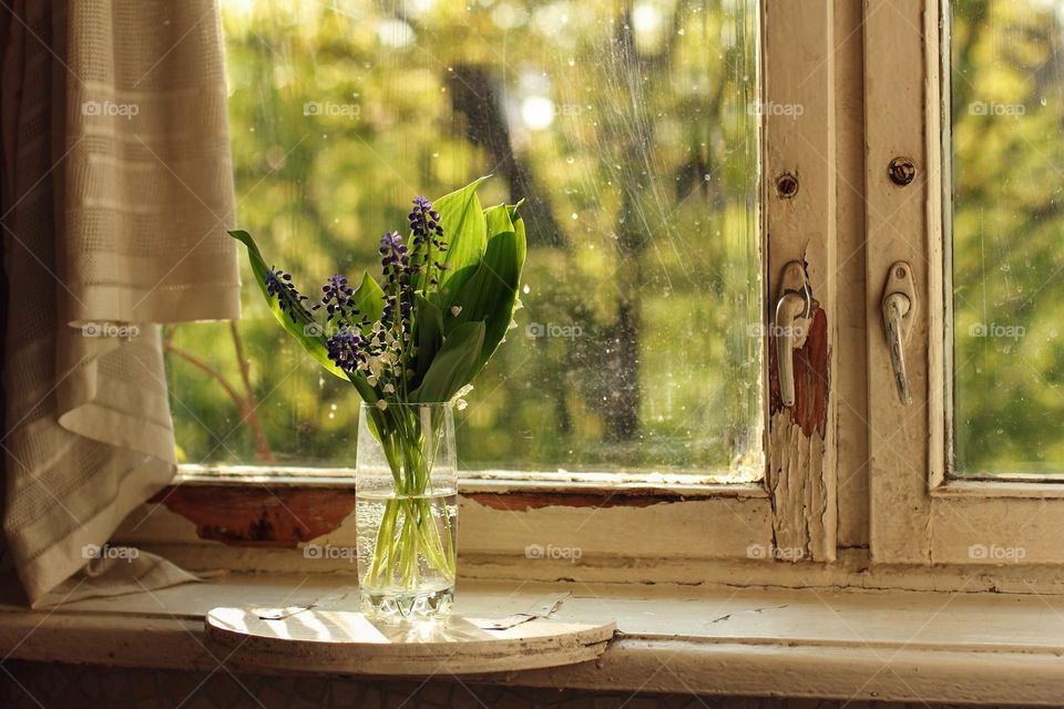 Lilies of the valley and muscari in a vase on an old windowsill