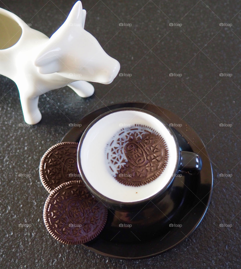 Oreo cookies with cup of milk and a cow creamer.