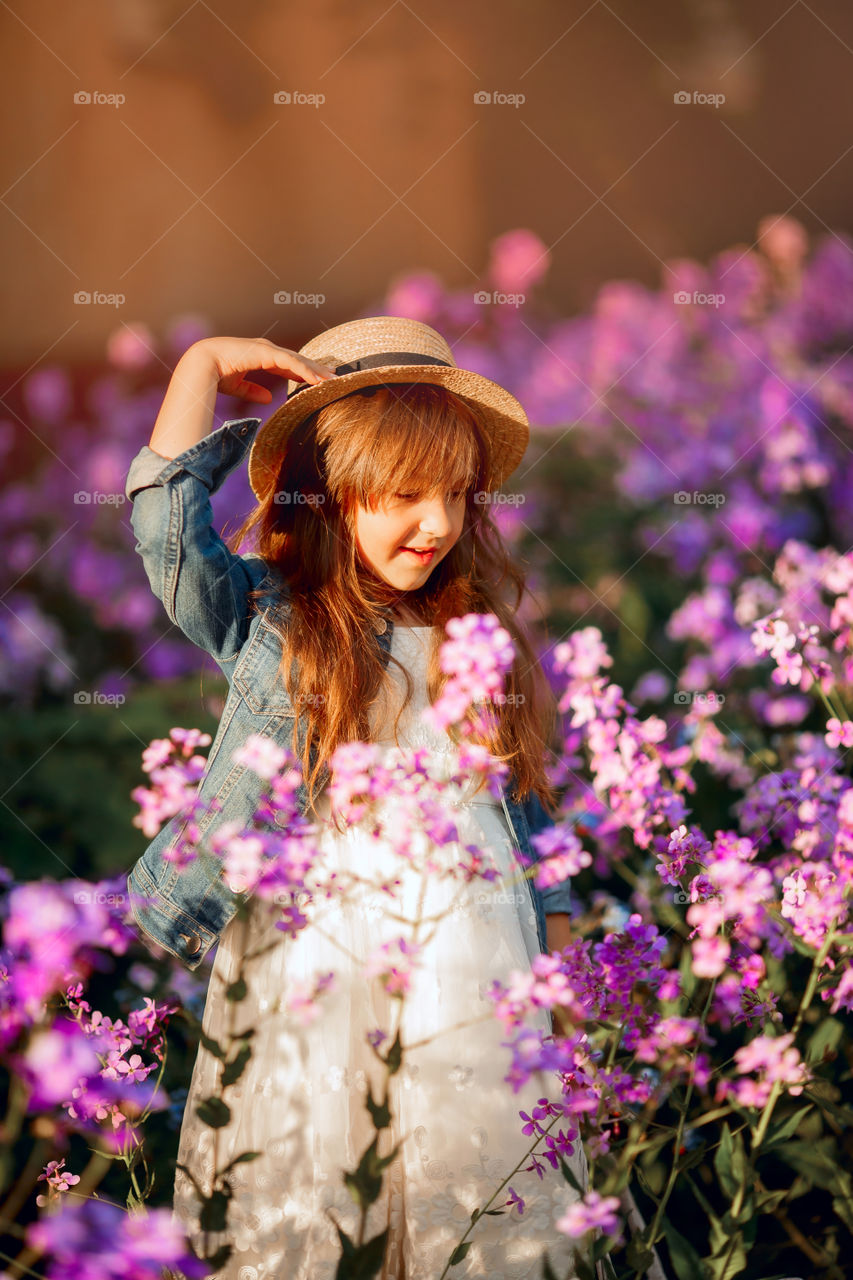 Cute little girl portrait in blossom meadow at sunset 