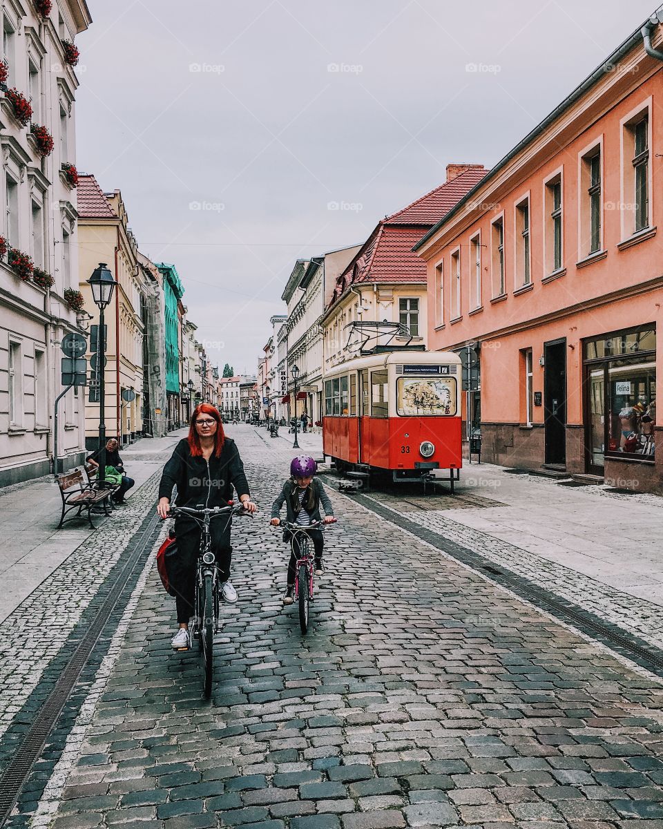 Girl bicycling with mother on street