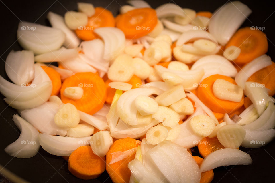 Onion, garlic, carrots in a frying pan ready to be cooked