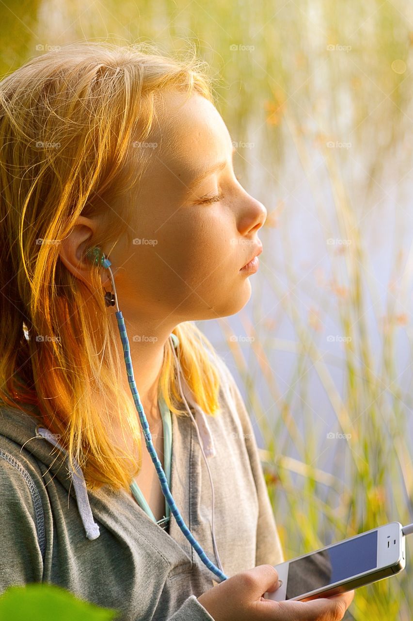 Relaxed. Girl listens to music while enjoying the sun