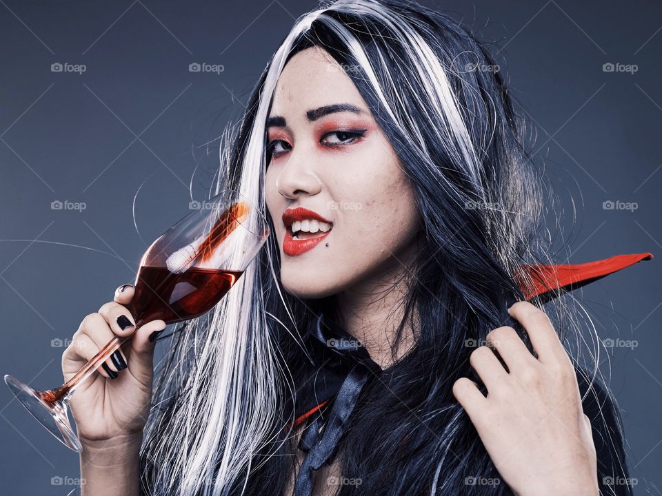 A vampire girl drinking blood from a glass