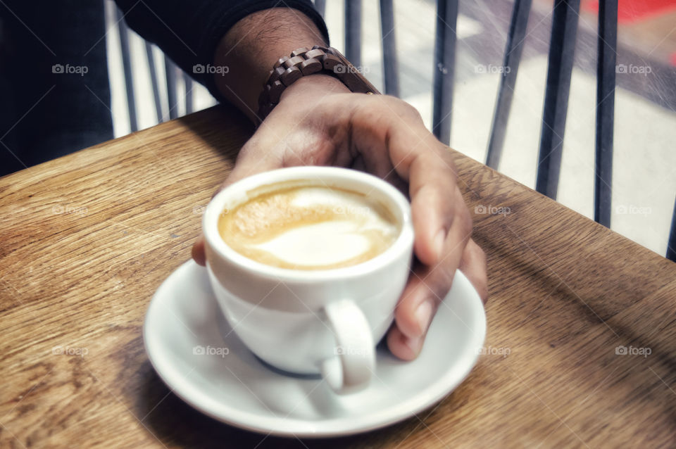 Hand grabbing a coffee cup.