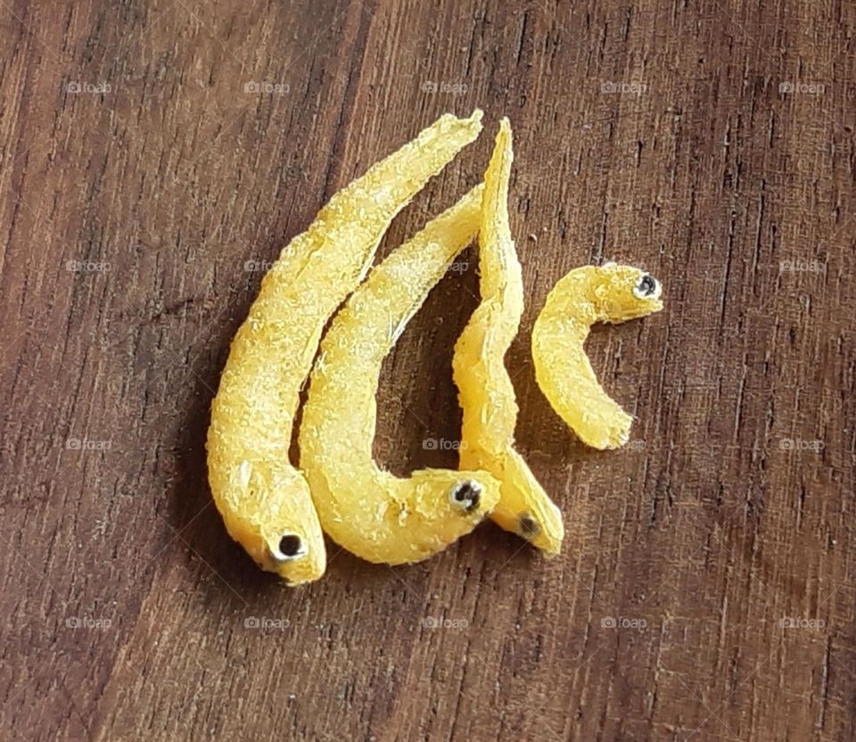 Tiny dried fish against wooden background