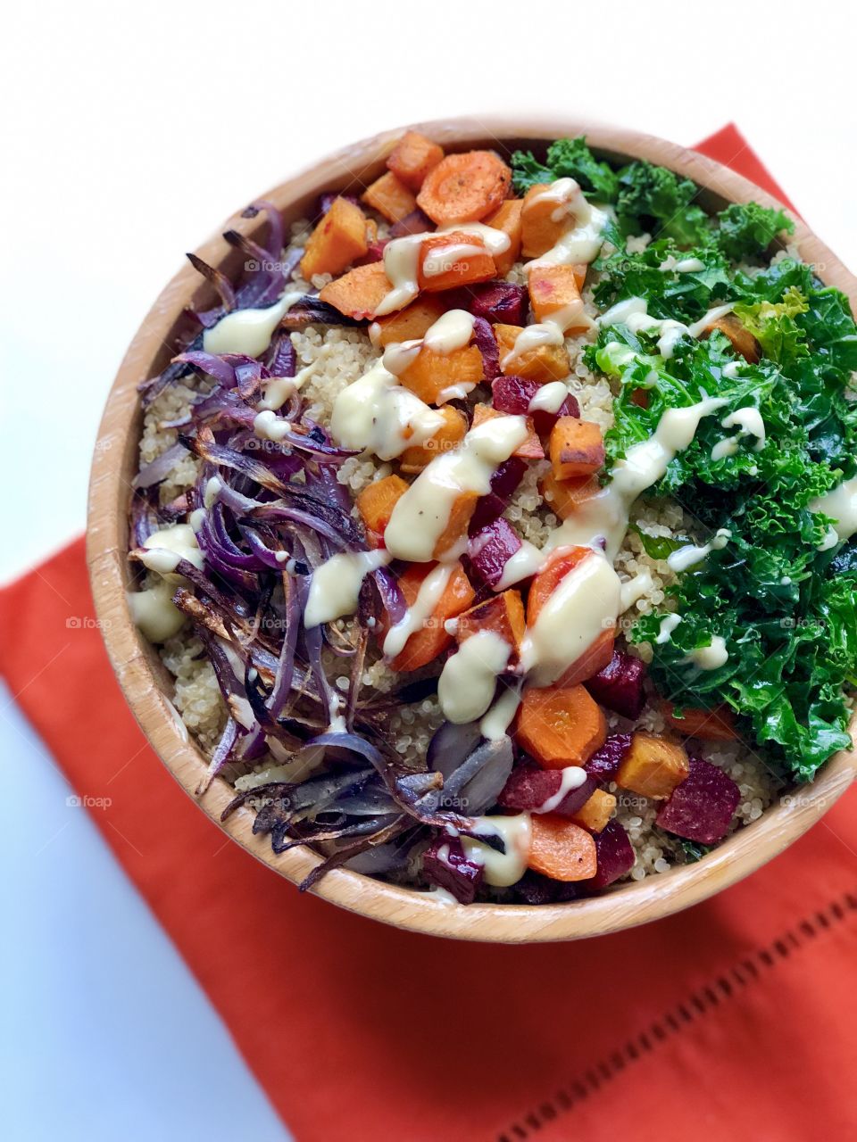 Colourful grain bowl topped with crunchy kale, nutritious carrots and roasted red onion. On a bed of quinoa and drizzled with creamy balsamic vinaigrette. 