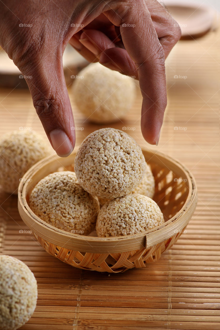 Indian food chaulai ke Ladoo in a wooden basket with a hand picking it up