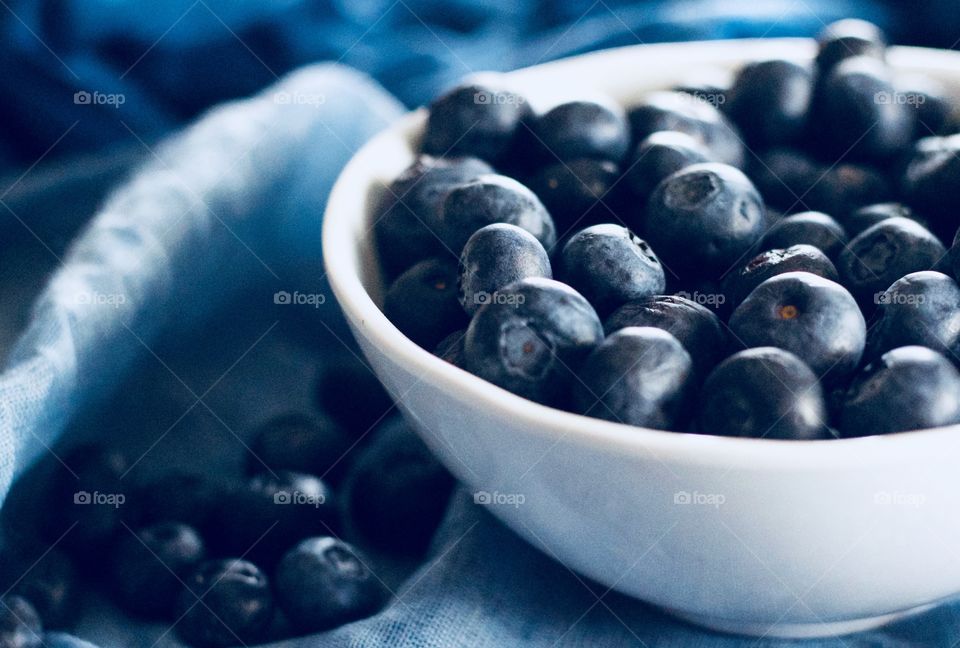 Fruits! - Blueberries in a white bowl and scattered on graduated blue fabric  